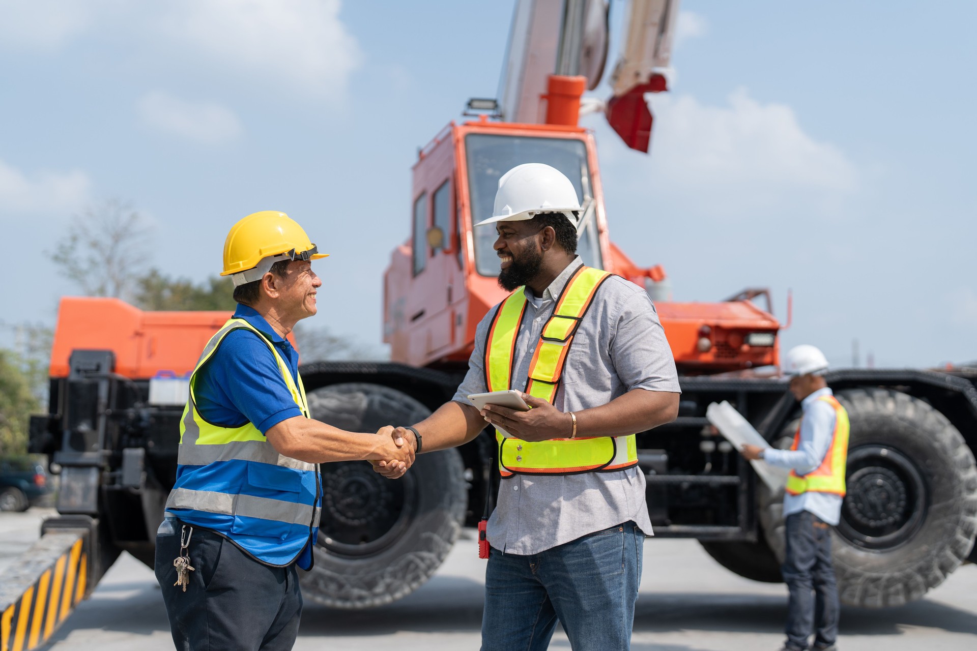 Asian Senior man supervisor foreman handshake with African American engineer for agreement rent mobile crane truck in construction site, Factory making precast concrete wall